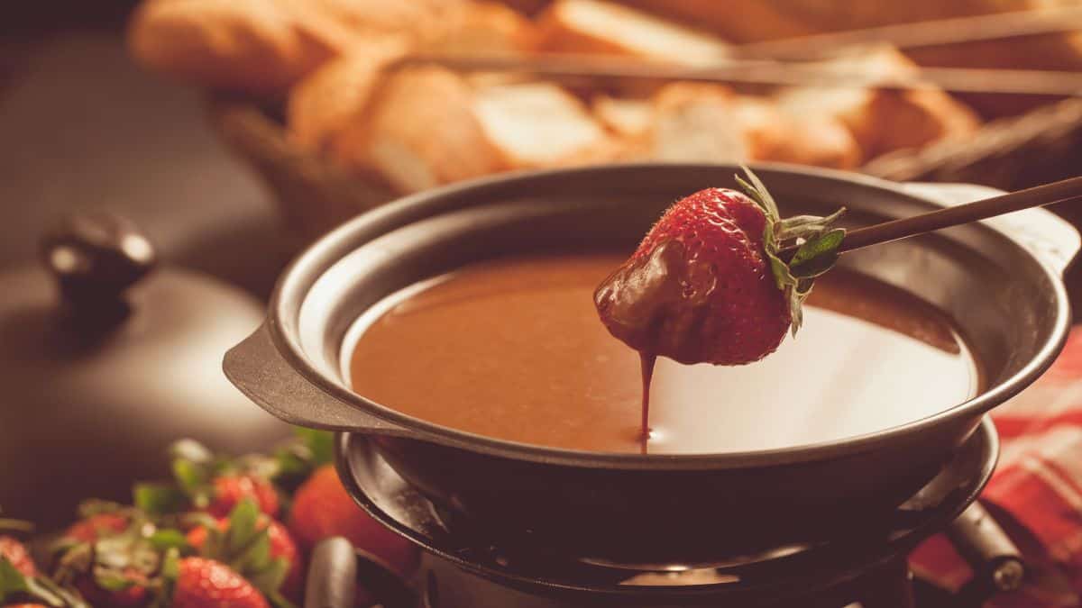 Une fraise trempée dans une fondue au chocolat.