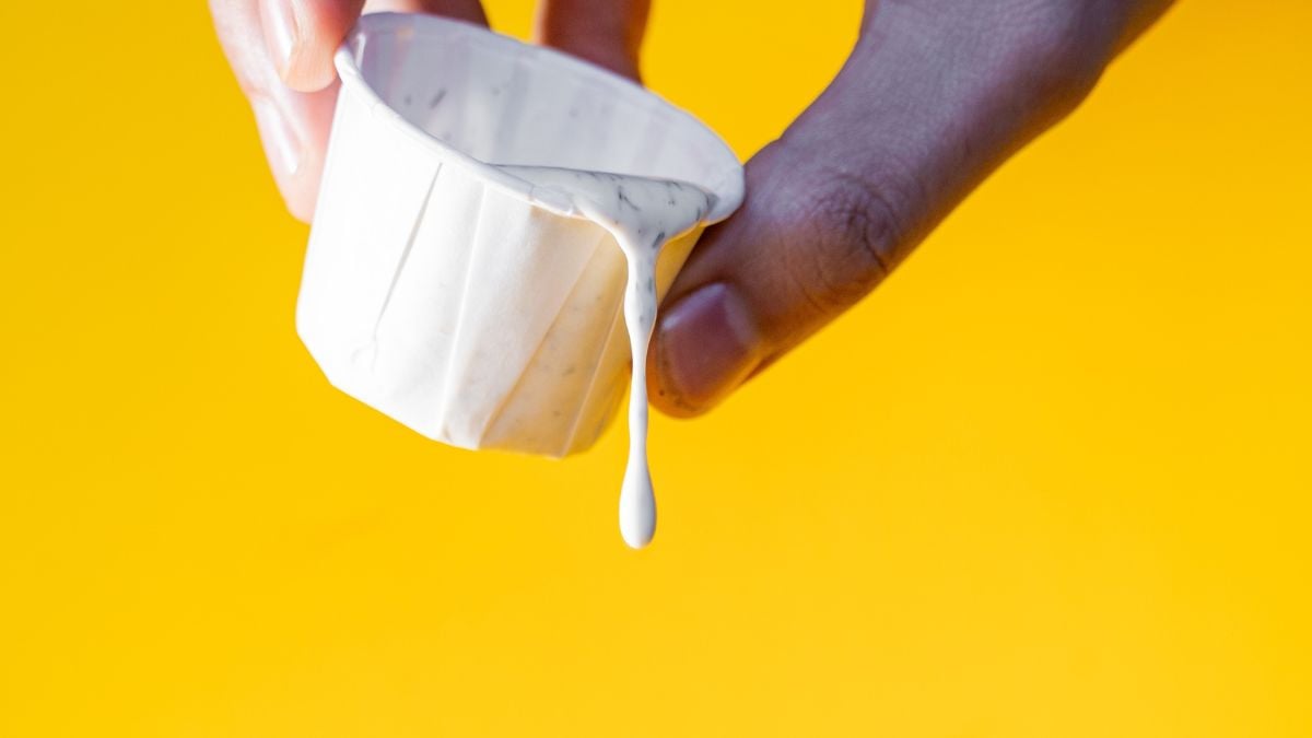 Une main versant de la sauce ranch.