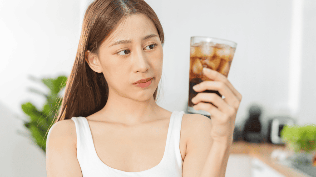 Une femme regardant un verre de Coca.