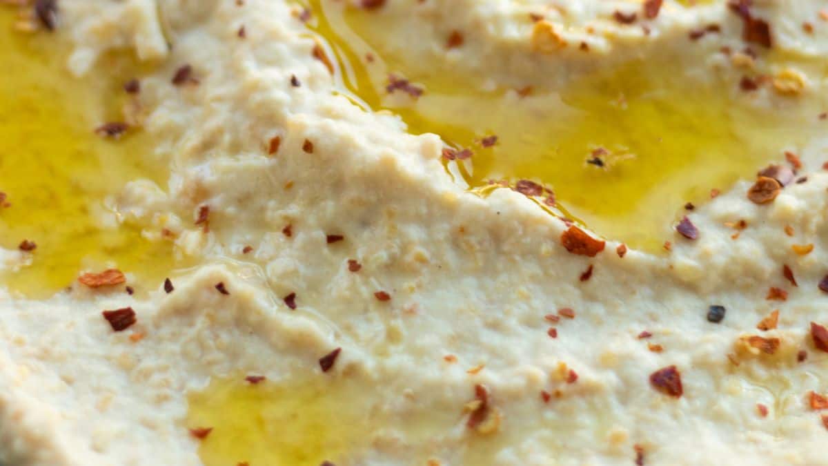 Houmous fait maison garni d'huile d'olive et de flocons de piment.