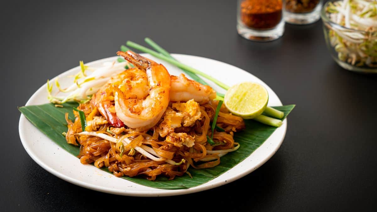 Une assiette de pad thai avec des crevettes.