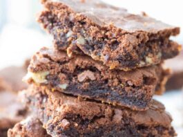 A stack of four walnut brownies showing their fudgy center.