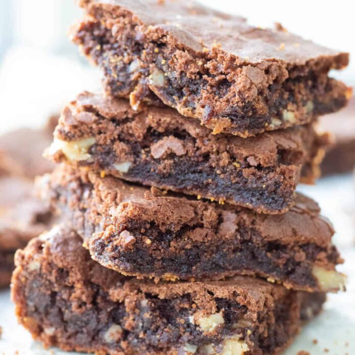 A stack of four walnut brownies showing their fudgy center.