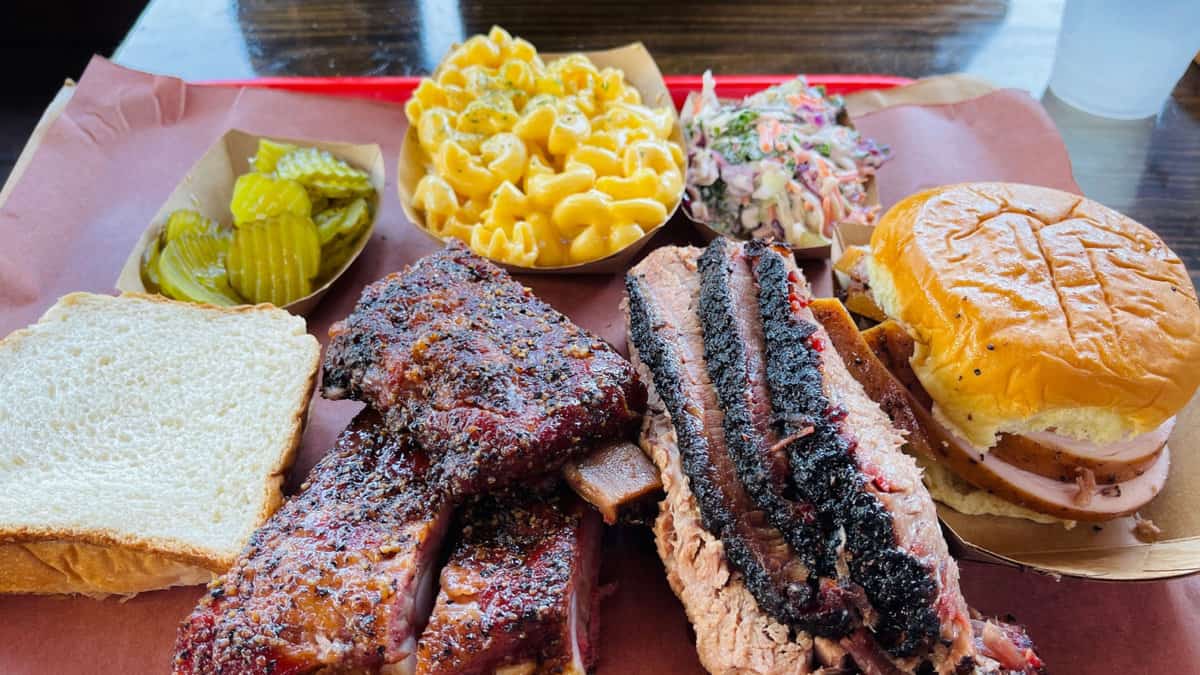 Un plateau de BBQ texan incluant du brisket et des côtes avec des accompagnements.