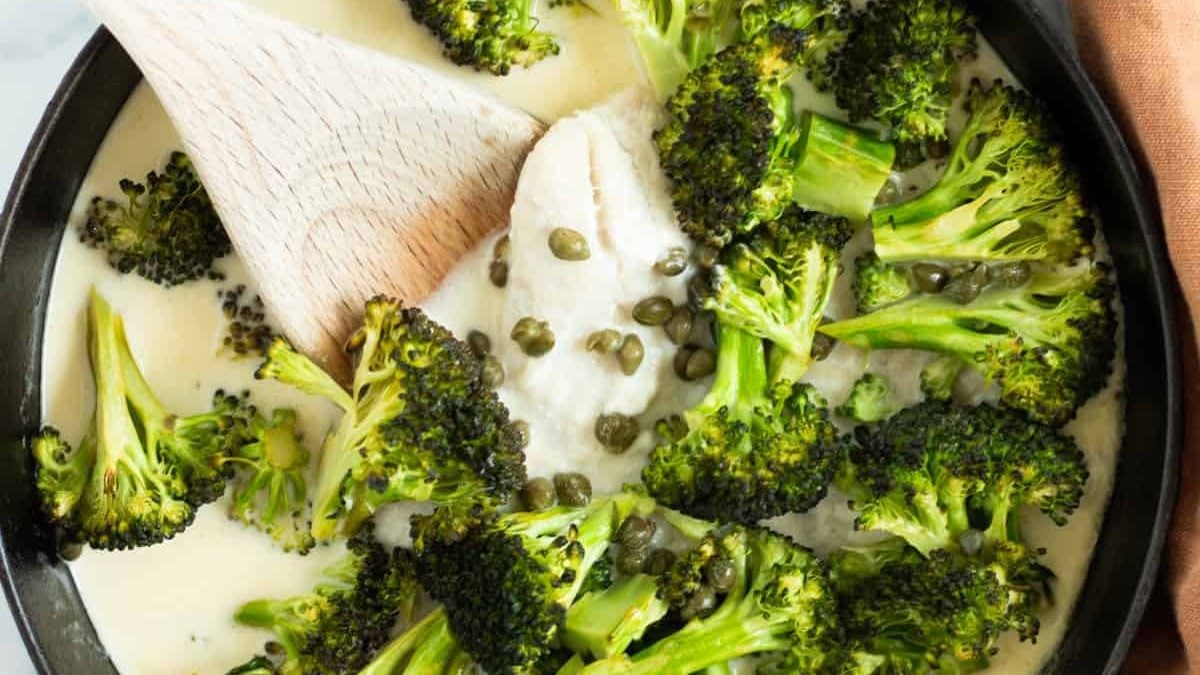 Une poêle pleine de poisson et brocoli dans une sauce citron câpres.