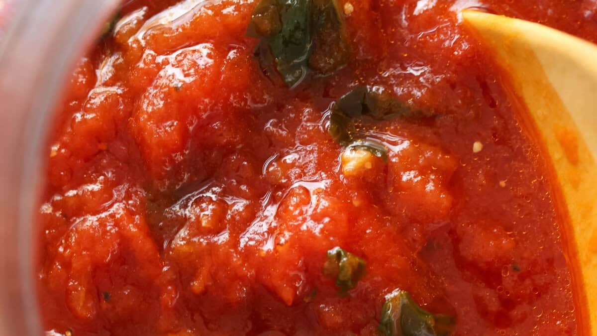 Gros plan d'un pot de sauce tomate maison avec basilic.