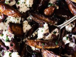 Close up of potato wedges topped with feta cheese and black olives.