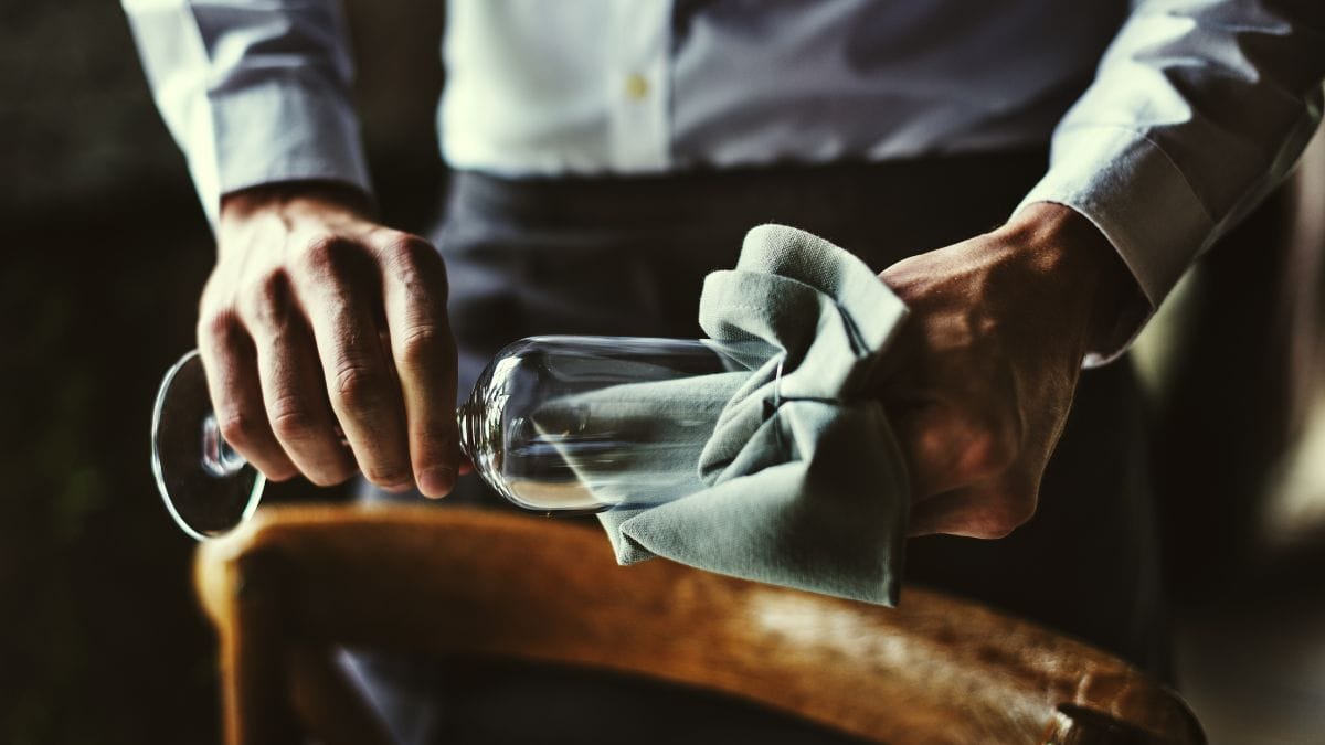 Un homme nettoyant un verre à vin.