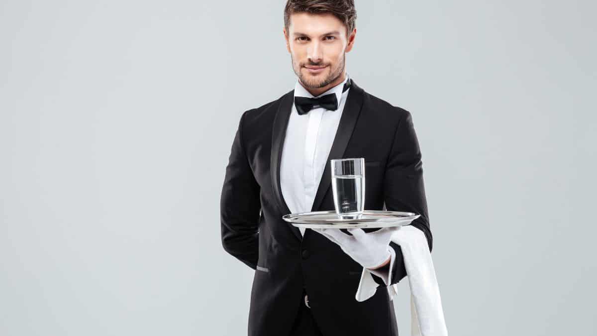 Un homme en smoking servant un verre d'eau.