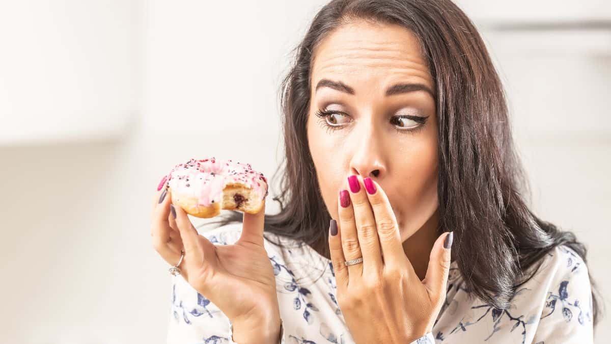 Une femme regardant un beignet.