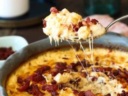 A spoonful of bacon mac and cheese being lifted out of the pan.