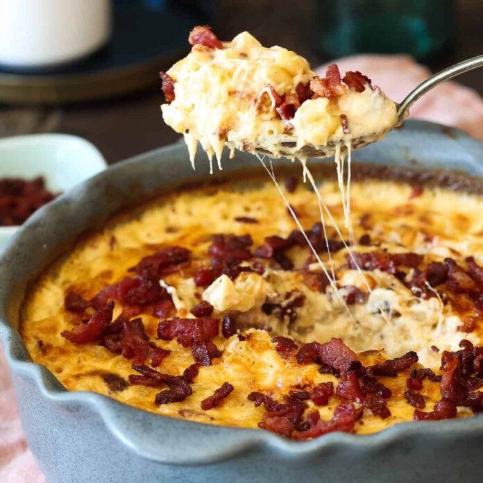 A spoonful of bacon mac and cheese being lifted out of the pan.