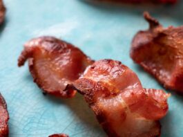 A slice of crispy air fryer bacon on a blue plate.