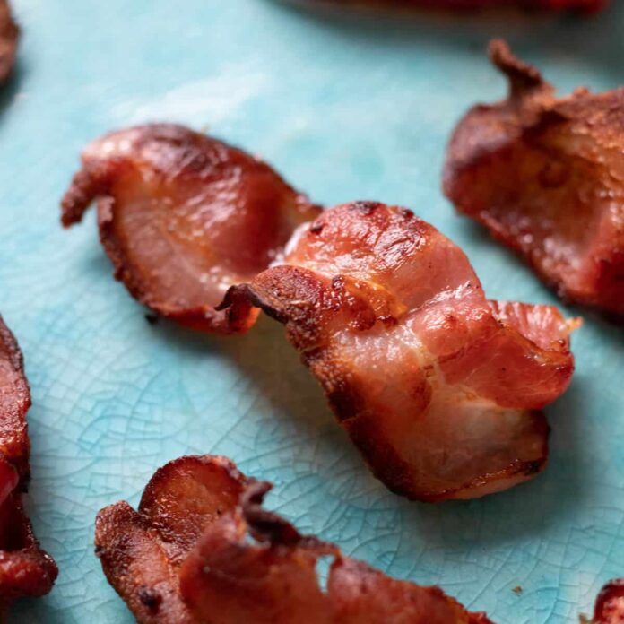 A slice of crispy air fryer bacon on a blue plate.