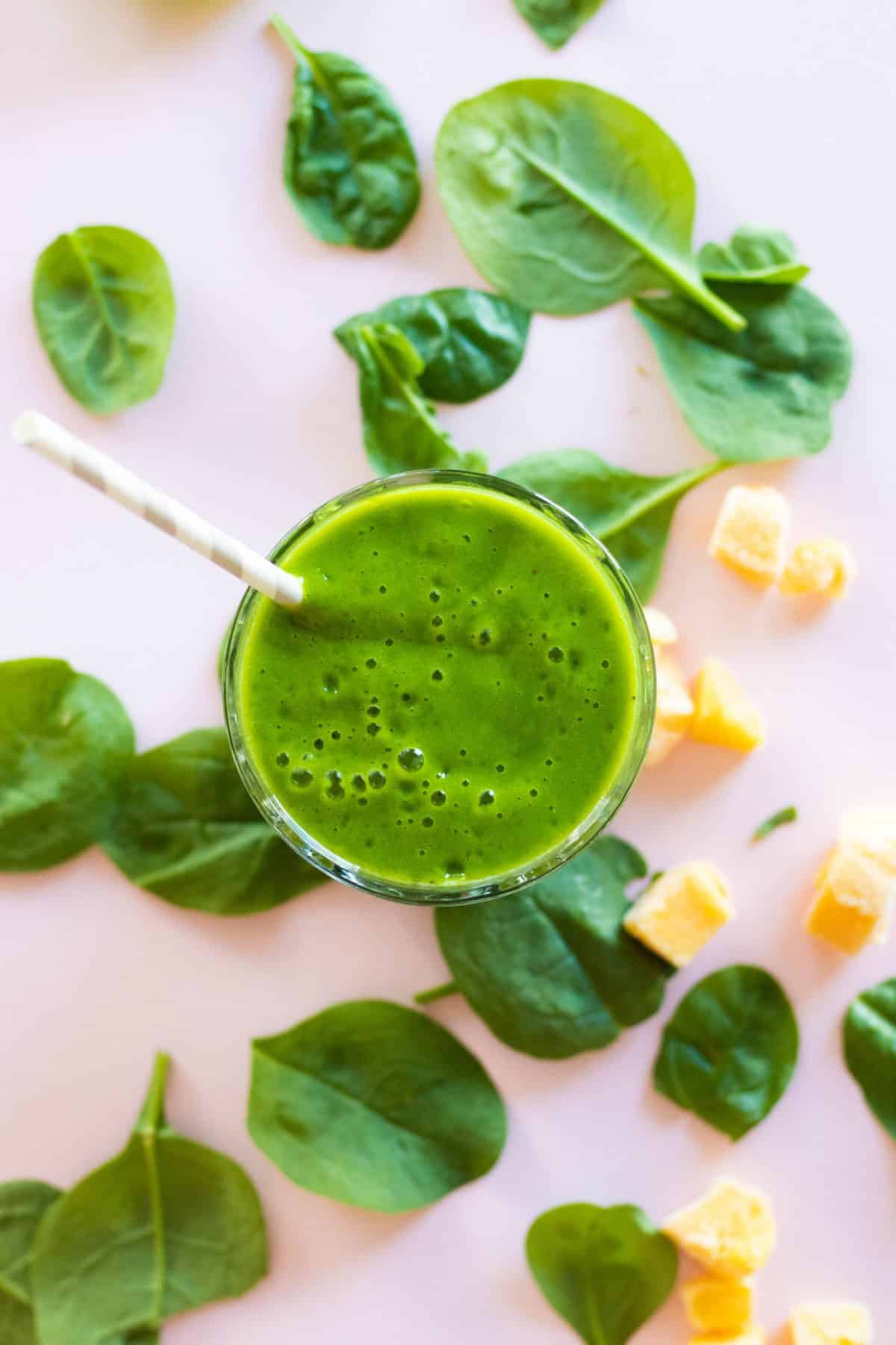 Vue du dessus d'un smoothie vert dans un verre avec une paille.