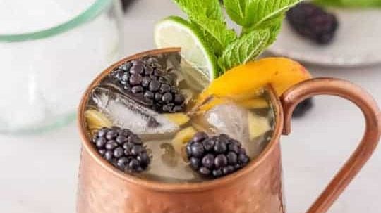 A cup with a blackberry peach mule mocktail.