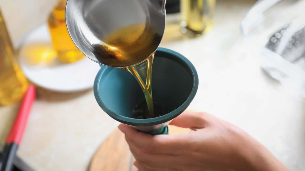 Une personne versant un liquide à travers un entonnoir.