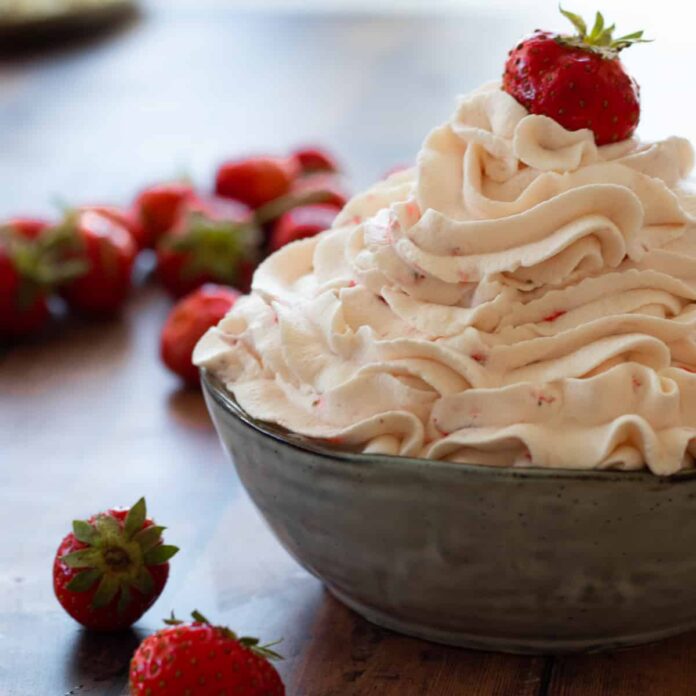 strawberry whipped cream in a bowl topped with a strawberry.